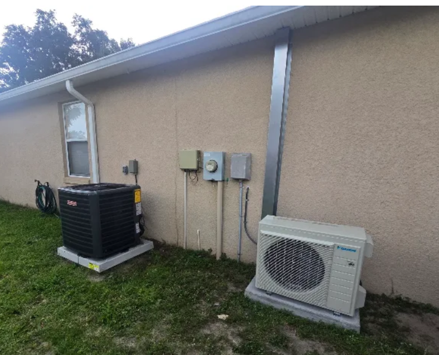 Outdoor condenser unit connected to new ductwork beside a second HVAC unit.